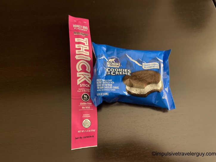 Honey BBQ flavored Slim Jim meat stick and Klondike Cookies & Creme ice cream sandwich on a dark wooden surface