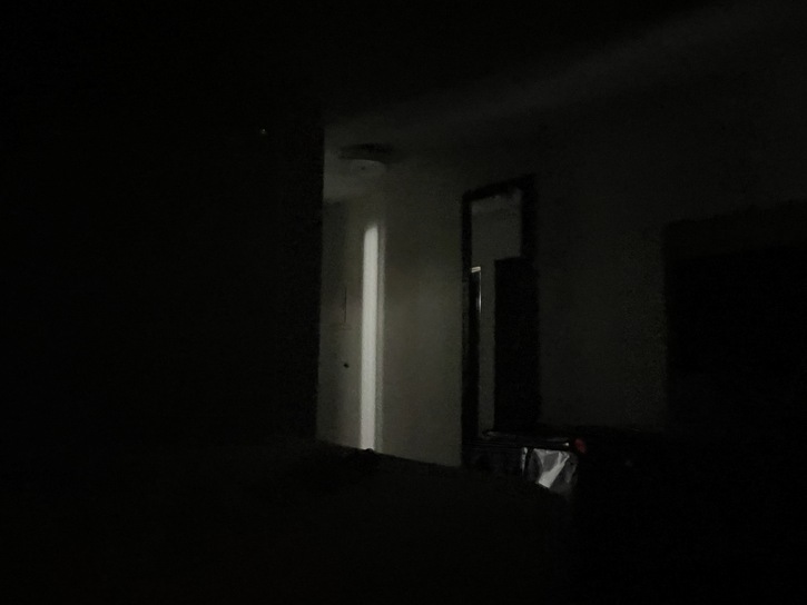 Dark interior photo showing dimly lit doorway with light coming through, minimal visibility