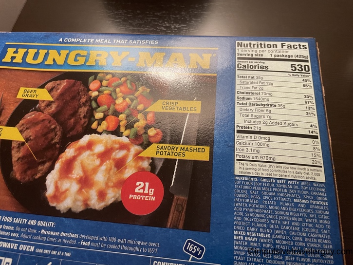 Back of a Hungry-Man frozen dinner box for salisbury steak meal, showing the product photo with beef patties, beer gravy, mashed potatoes, and mixed vegetables. Nutrition facts panel shows 530 calories and 21g protein per package.