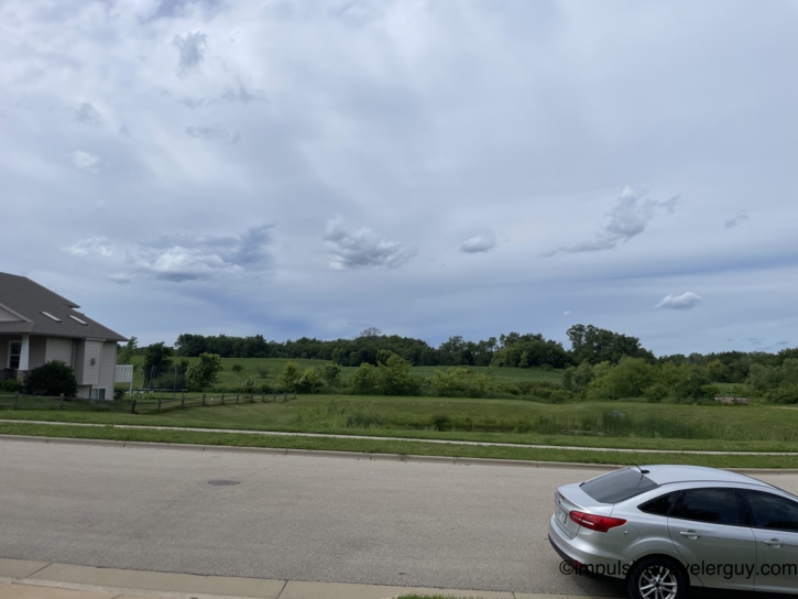 Back home in Belleville — the silver Ford Focus parked on the street in front of the house, overcast skies building over green fields in the background after the day's clear weather.