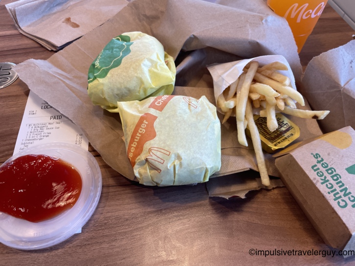 McDonald's meal spread on a tray with two cheeseburgers, fries, Chicken McNuggets, ketchup cup, and a Hi-C Orange drink with receipt visible.