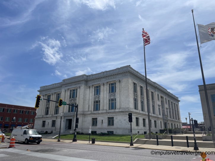 Madison County Courthouse, a grand white limestone neoclassical building with Corinthian pilasters, American and Illinois state flags flying out front.