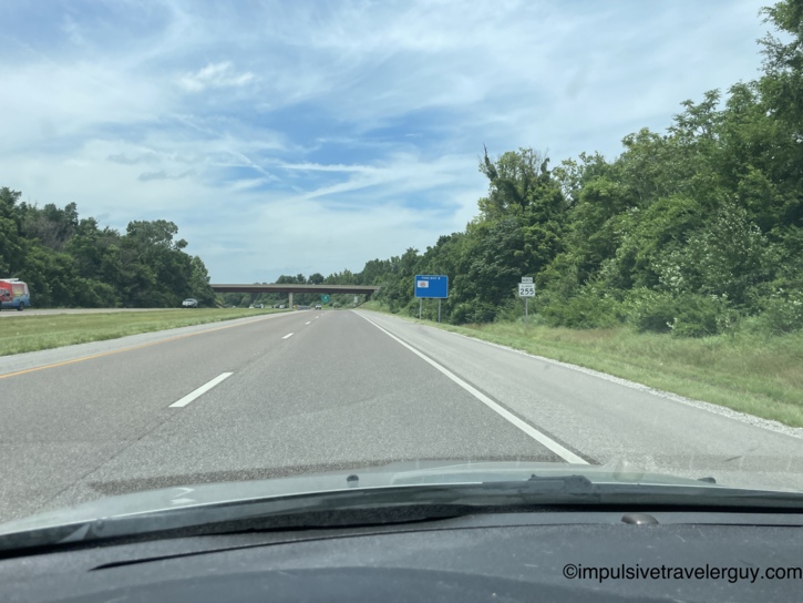 Driving north on Illinois Route 255 passing a food services exit sign and highway overpass through green wooded corridor.