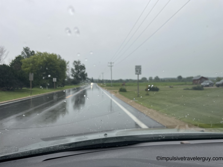 Driving through heavy rain on a rural two-lane highway with a Route 92 sign visible ahead.