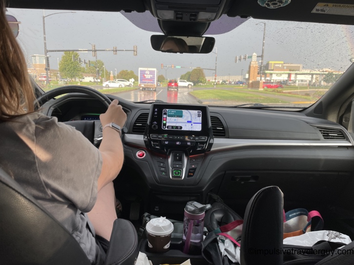 View from the back seat showing Victoria driving the van through rainy weather as they approach Wisconsin.