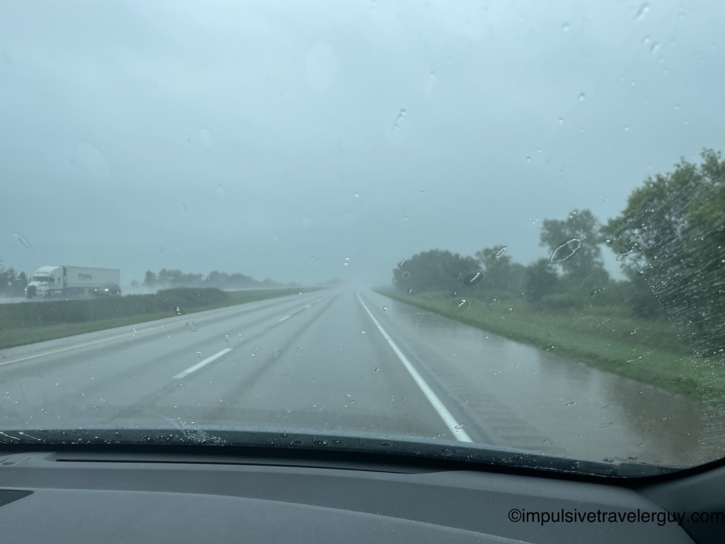 View through a car windshield covered in raindrops while driving on an Illinois highway on a dark, overcast day.
