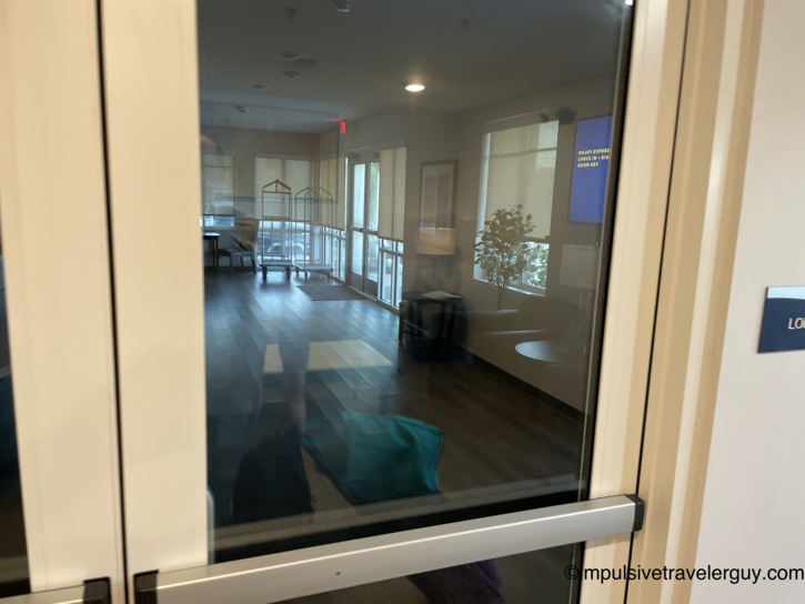 View looking through locked glass doors into a dark, closed hotel lobby.
