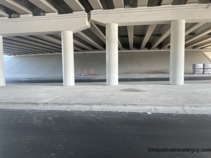 View underneath a clean, massive concrete highway overpass in Austin supported by thick pillars.