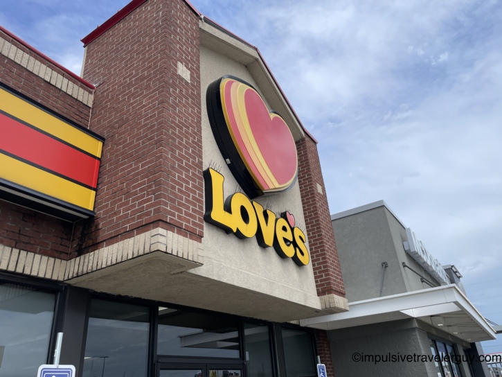 Exterior view of a Love's Travel Stop building featuring its signature red heart and yellow text logo on a brick facade.
