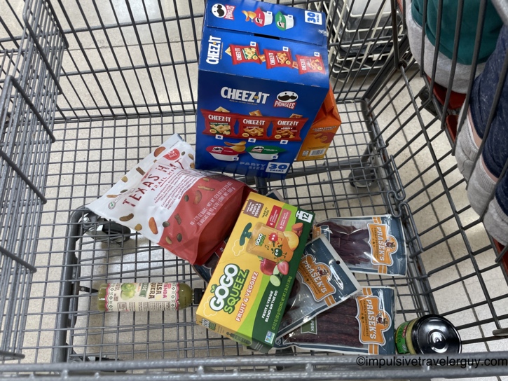 A shopping cart filled with essentials for the road trip home, including snacks, trail mix, Prasek's beef jerky, and salsa.