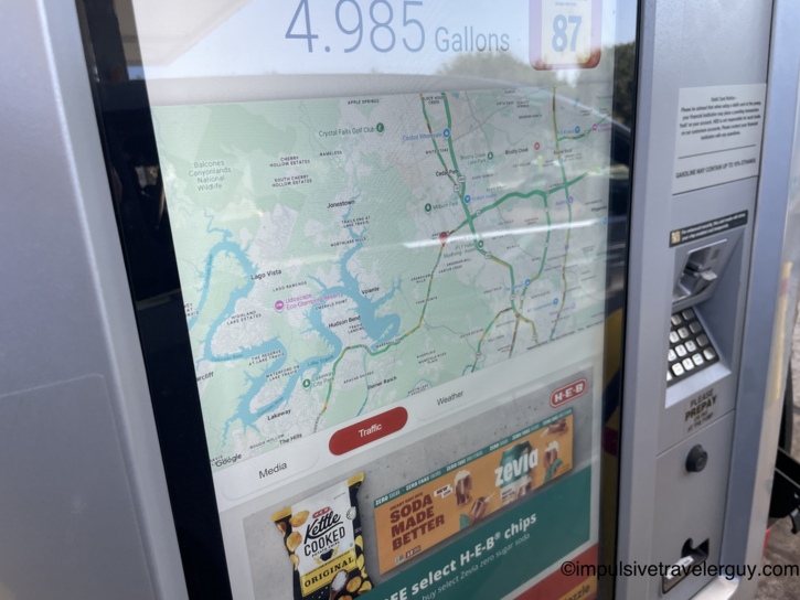 Close-up of a modern gas pump touch screen displaying a local traffic map of the Lake Travis area and the fuel meter.