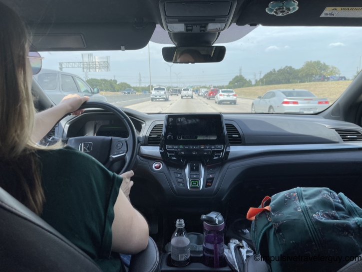 View from the back seat wedged between the kids, showing Victoria driving the van on the highway.